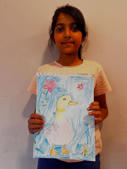 A proud student holds up her finished duck artwork, a wonderful result from one of our guided drawing and coloring sessions.