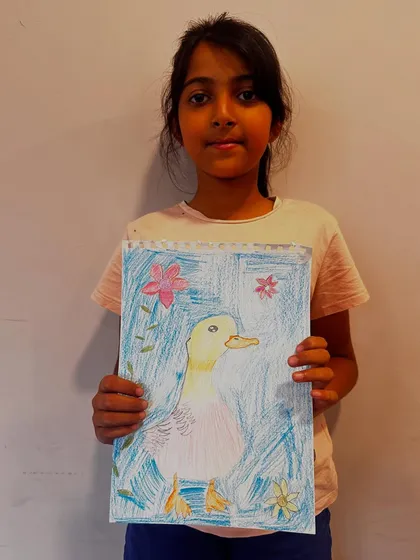 A proud student holds up her finished duck artwork, a wonderful result from one of our guided drawing and coloring sessions.