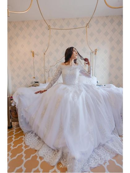 A beautiful portrait of the bride on her bed, the full expanse of her gorgeous wedding dress on display.