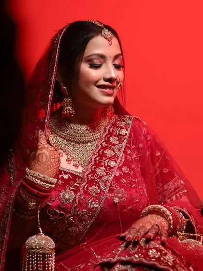 A seated portrait of the bride, her red lehenga and kalire beautifully captured. Her gentle smile makes the photo warm and inviting.