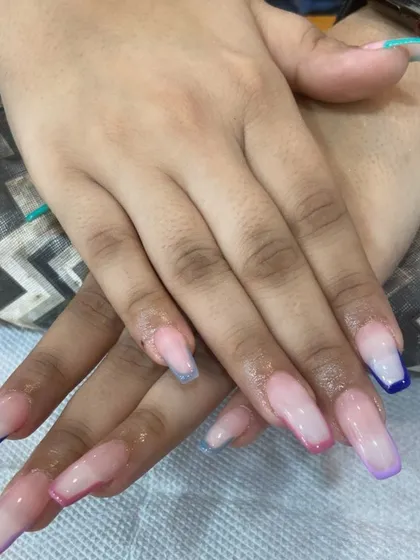 A fun and colorful French manicure on square-shaped extensions. Each nail has a different colored tip, including shades of blue, purple, and pink, for a playful and modern style.