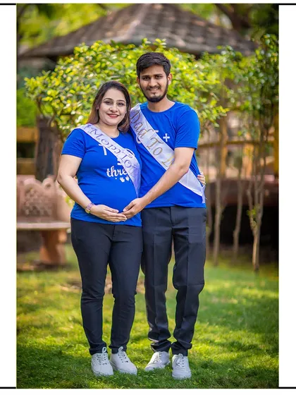 A proud portrait of the parents-to-be in matching t-shirts and celebratory sashes.