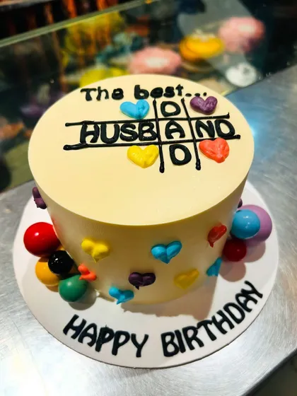 A fun and creative birthday cake for a husband, designed as a winning game of tic-tac-toe that spells out "Husband".
