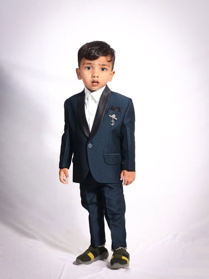 This little gentleman is looking sharp in his formal suit. A full-length studio portrait against a clean white background highlights his dapper outfit and confident stance.
