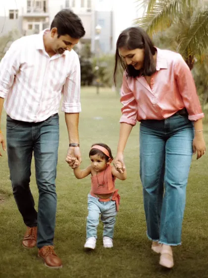 Capturing a toddler's first steps is a precious milestone. Here, we photographed parents gently guiding their child as they walk together during a family session in a park.