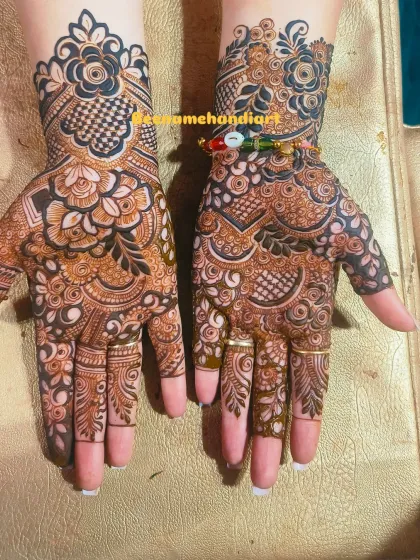 A pair of hands with matching floral and checkered fusion mehandi. The design on the back of the hand is just as important as the front.