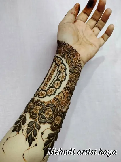 A unique design featuring a decorative cuff on the forearm, complemented by a trail of roses. The use of negative space makes the artwork pop.