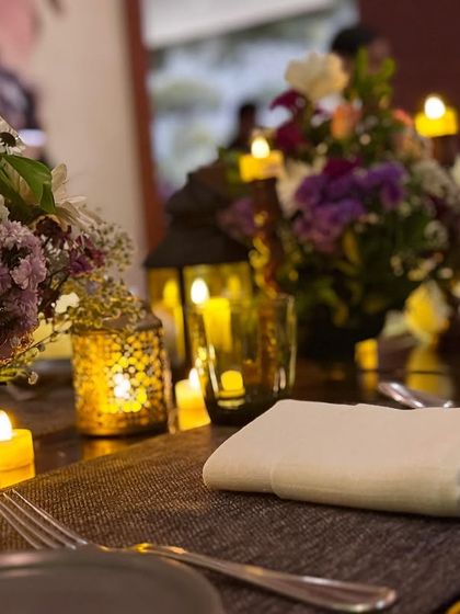 The warm glow from the candles and lanterns creates a cozy and inviting atmosphere for any dinner party.