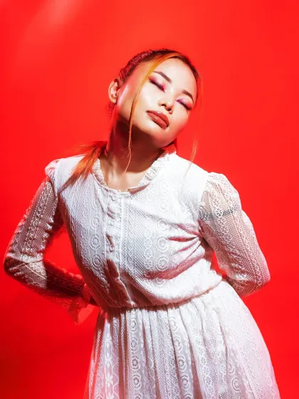 This image showcases a soft, romantic makeup look that contrasts beautifully with the intense red lighting of the editorial shoot.