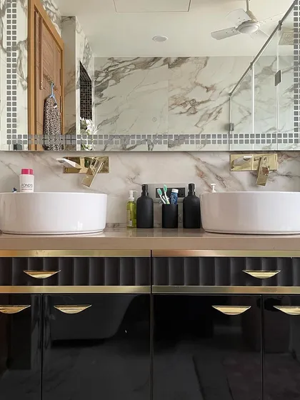 A bathroom should be a personal sanctuary. In this design, we contrasted the beautiful natural veins of Calacatta marble with a bold, black double vanity. The custom unit features fluted details and brushed gold hardware for a touch of timeless glamour.