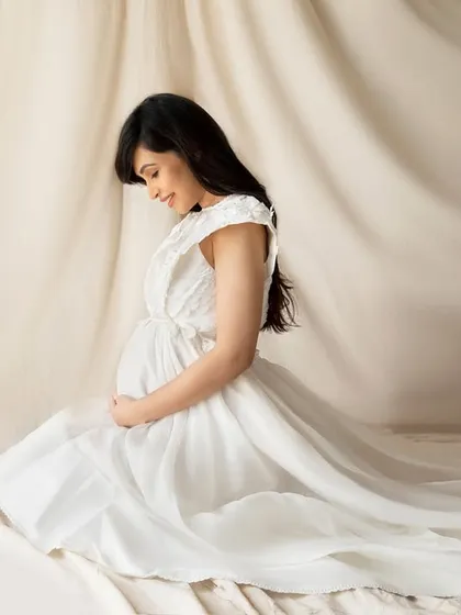 Kneeling in a flowing white gown against a draped beige backdrop. This pose creates a lovely, gentle silhouette that is both humble and powerful.