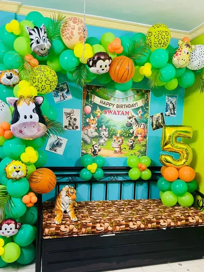 A fun jungle animal themed decoration set up in a room. It features a green balloon garland with various animal-head foil balloons and a personalized "Happy Birthday" poster.