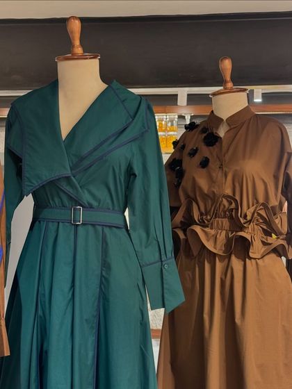 A display of well-tailored dresses and trench coats in earthy tones of green and brown, perfect for a sophisticated, structured look.