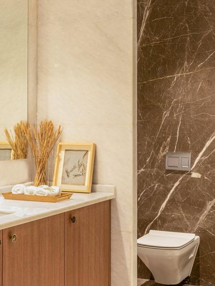 A detail shot of the brown marble and wood vanity in this bathroom. The clean lines of the wall-mounted toilet and the simple, elegant accessories contribute to a modern and uncluttered aesthetic.