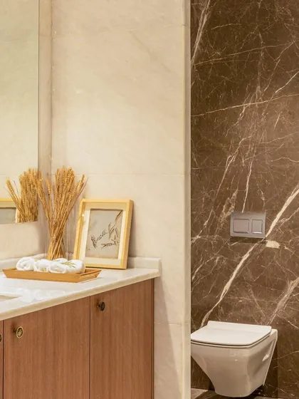 This washroom design elevates functionality into a spa-like escape. The contrast between the dark, veined marble and the light wood vanity creates a luxurious and relaxing atmosphere.