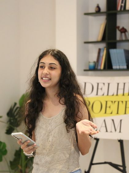 A high school student sharing her poem with a smile. Our events are a great starting point for young writers looking to gain confidence and stage experience.