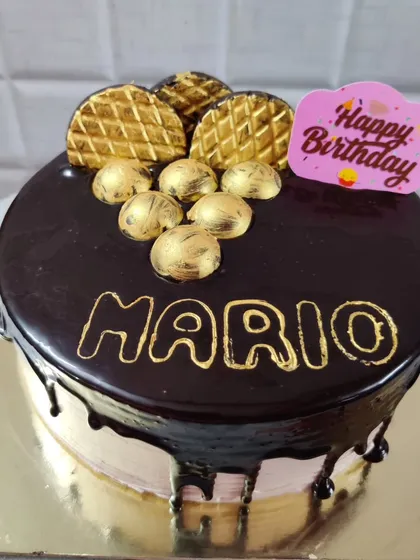 A rich chocolate drip cake for Mario's birthday. This design is topped with golden chocolate decorations for an extra touch of class.