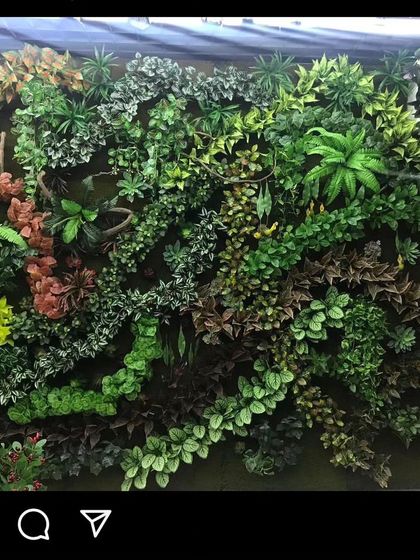 A highly detailed and textured green wall with a wide variety of artificial plants. This "wild jungle" style is perfect for creating a dramatic feature wall.