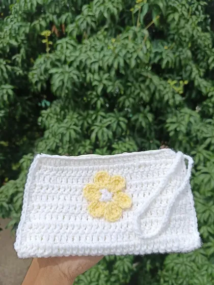 A simple white pouch with a yellow flower applique. This clean and fresh design is perfect for a spring or summer collection.