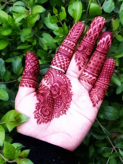 An intricate party henna design focused on the palm and fingers, with a deep, rich stain.