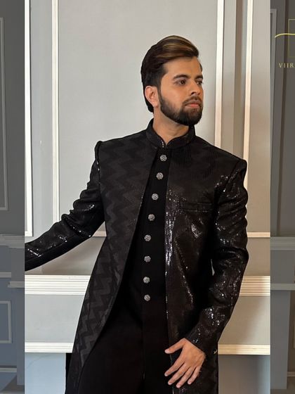 A close-up of the black textured sherwani, highlighting the unique fabric and sharp shoulder construction.