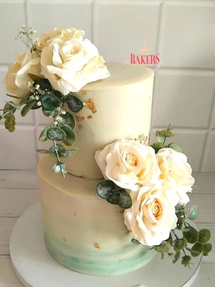 A stunning pastel green and white two-tier engagement cake, proving that simple and classic is always beautiful. I adorned this no-fondant cake with fresh white roses and eucalyptus for a fresh, elegant feel.