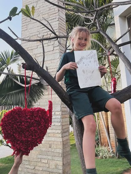 A student perches in a tree to show off her panda sketch, combining a love for art with a bit of outdoor fun.