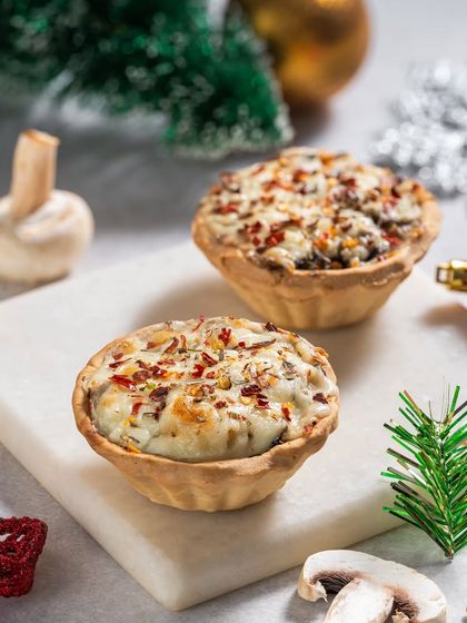 Savory mushroom tarts with a cheesy topping, styled with Christmas decor for a holiday menu feature.