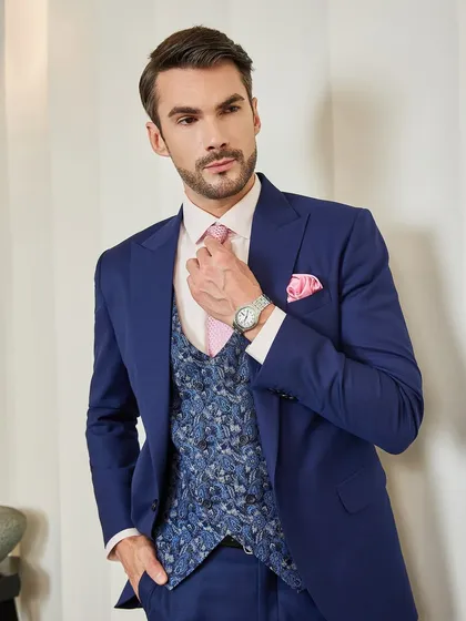 Adjusting the tie, this shot focuses on the details: the peak lapel, the textured waistcoat, and the pop of color from the accessories. It's a masterclass in sartorial style.