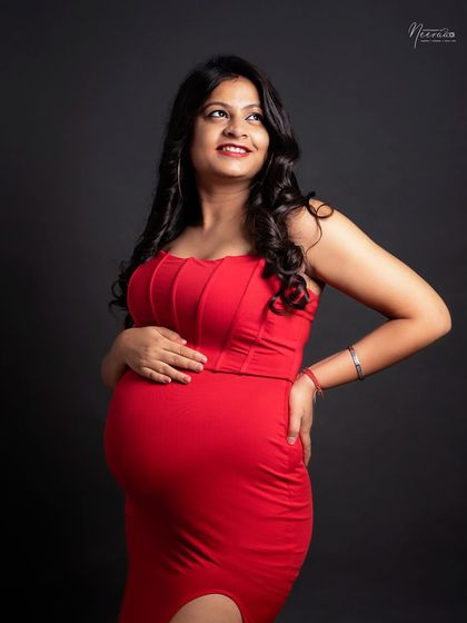 A joyful and candid moment. Her upward glance and bright smile capture the pure happiness and excitement of waiting to meet her baby.