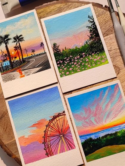 A close-up of four polaroid paintings, showing the details in the palm trees, flowers, and sunset clouds.
