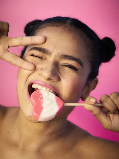 Playful and edgy, this shot with a heart-shaped lollipop against a vibrant pink background is perfect for a youth-focused brand or confectionery product.
