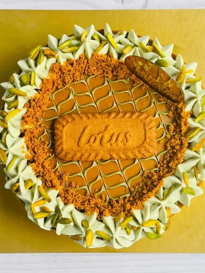 This angle highlights the creamy texture of the pistachio-infused whipped topping that surrounds the central Biscoff design.