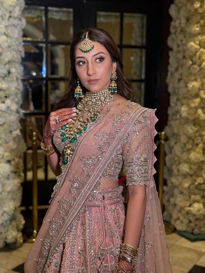 A beautiful shot against the backdrop of floral decor, highlighting the intricate embroidery on her lehenga and the soft tones of her makeup.