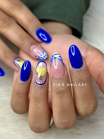 Vacation nails in a vibrant blue, with accent nails featuring hand-painted lemons and tile patterns.