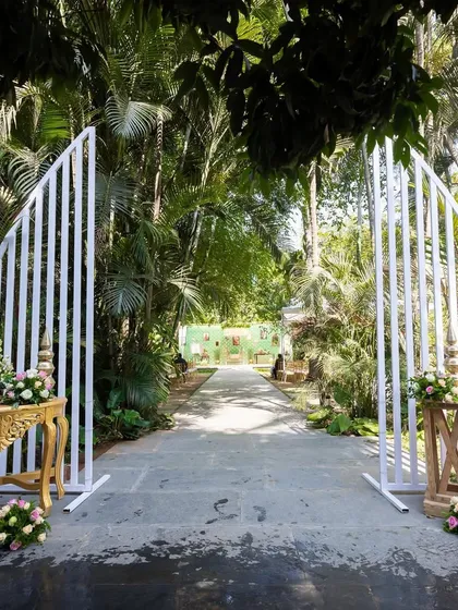 The entrance to the naming ceremony, featuring modern white arches that lead into a lush, green garden venue.