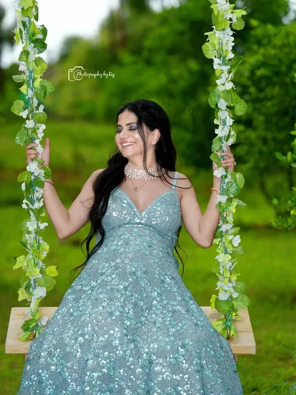 A happy and relaxed moment on our floral swing. The sparkling blue gown shimmers in the natural light, adding a touch of glamour to this outdoor maternity portrait.