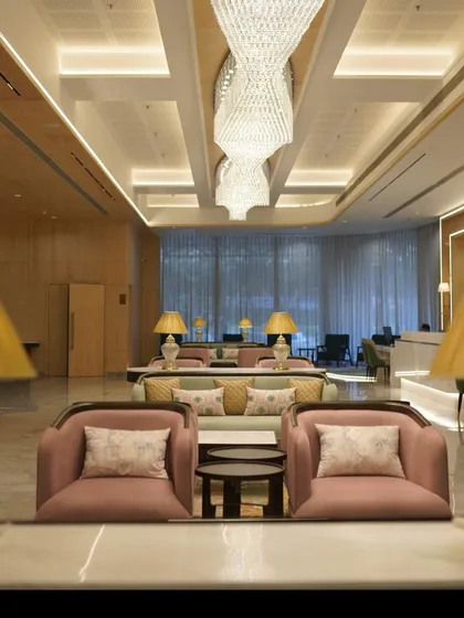 The grand lobby of the GCC Hotel and Club, featuring a flowing crystal chandelier and a sophisticated color palette. The design creates an inviting ambiance that redefines hospitality.