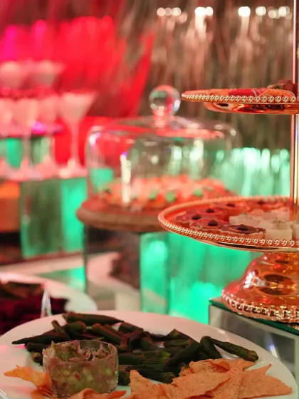 A colourful dessert buffet under green and red lights, featuring tiered stands of sweets and pastries.
