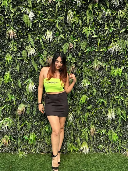 A full-length shot of the neon top outfit. The green wall background makes the neon color pop even more.