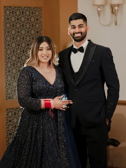 A classic portrait of the couple at their reception. Their coordinated navy blue and black outfits, combined with their happy smiles, create a picture of elegance and joy.