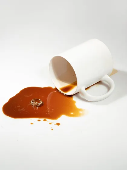 A conceptual and unexpected shot of a ring in a puddle of spilled coffee. This creative idea is memorable and adds a touch of wit and artistry to the product photography.