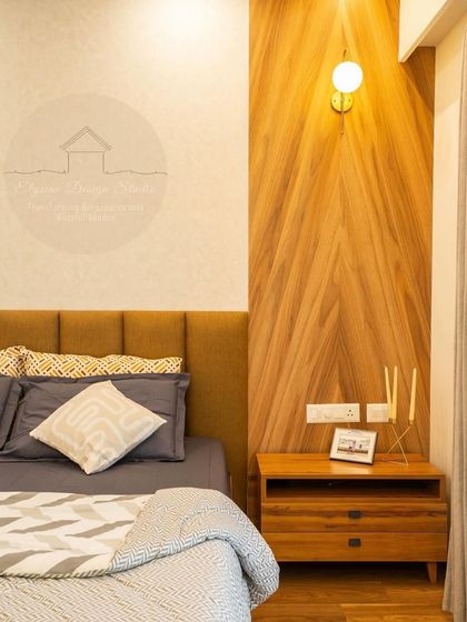 A close-up of the master bedroom's bedside, showing the custom wood paneling, upholstered headboard, and simple, elegant decor.