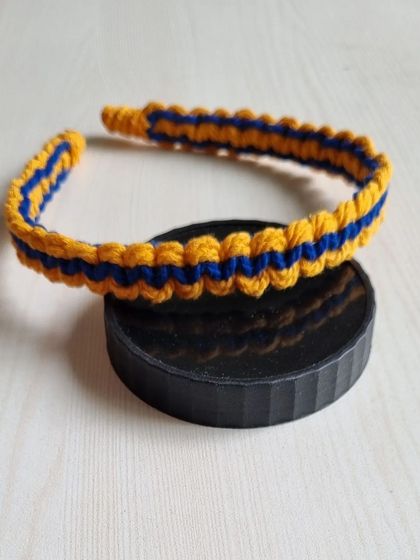 A two-tone macrame headband in yellow and blue, showcasing a different knotting pattern for a unique look.
