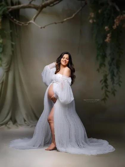 A joyful and candid shot in a beautiful white gown. The mother-to-be's happy expression and the elegant setting create a picture of pure bliss.