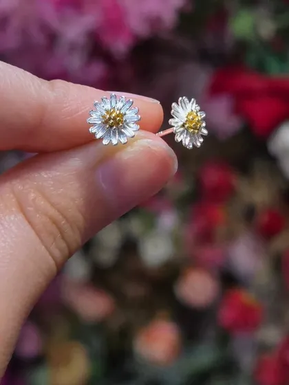 A pair of delicate daisy studs in sterling silver with gold-plated centers. A sweet and charming piece of nature-inspired jewellery.