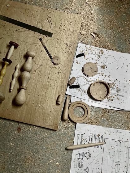 From sketch to reality. Our design drawings lie on the workshop floor next to the first physical prototypes of the Channapatna modules, illustrating the journey from a concept to a tangible, handcrafted object.