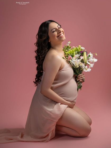 That third-trimester glow is real! A joyful, candid moment of a mama-to-be, laughing with a bouquet of flowers. This photo is pure happiness and light.