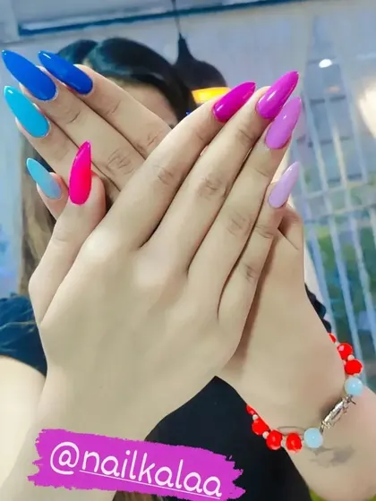 A bold and confident look with each nail painted a different solid, vibrant color, including shades of blue, pink, and purple.