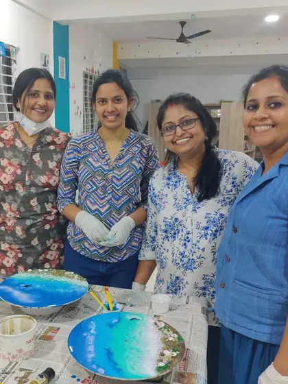 A happy group photo of our participants after a successful resin art workshop, proudly standing behind their almost-finished creations.